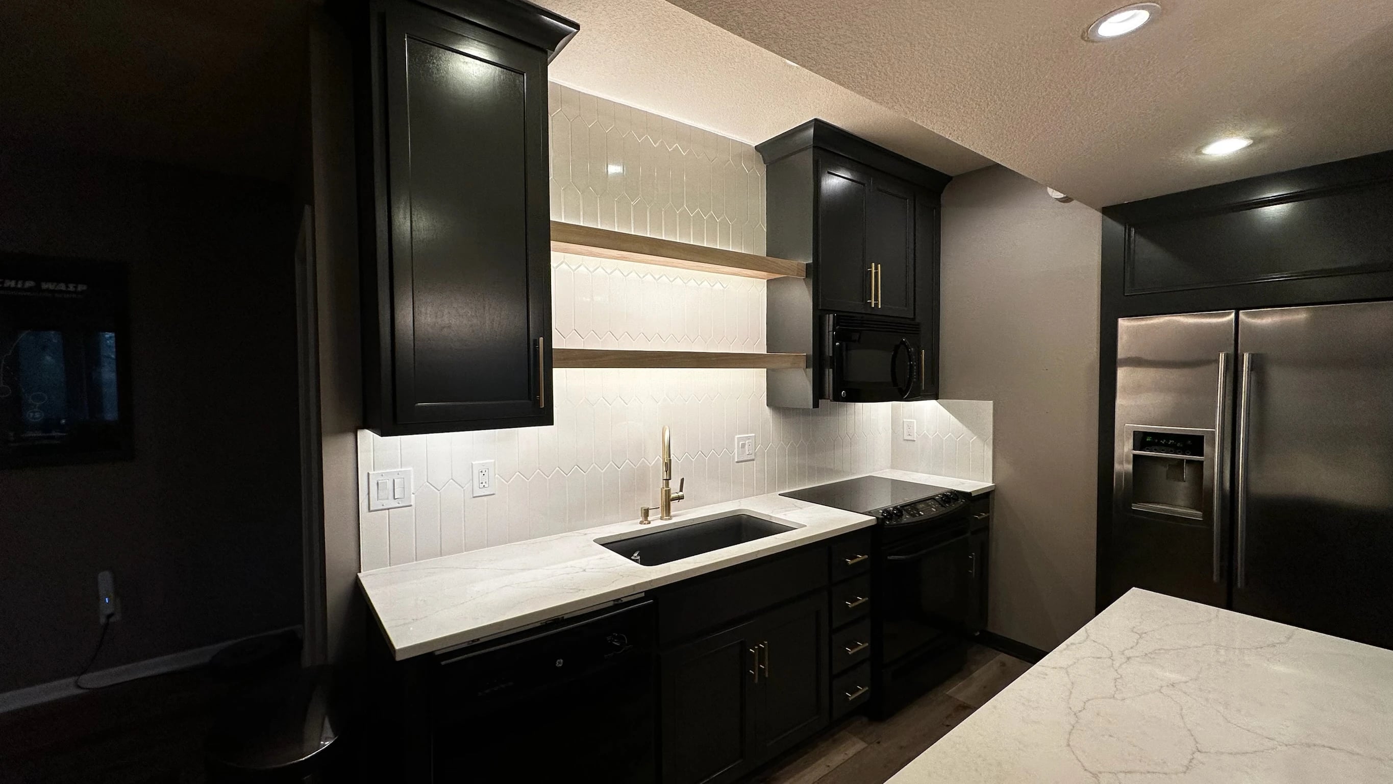 Dark cabinetry, sink and appliances in secondary kitchen space