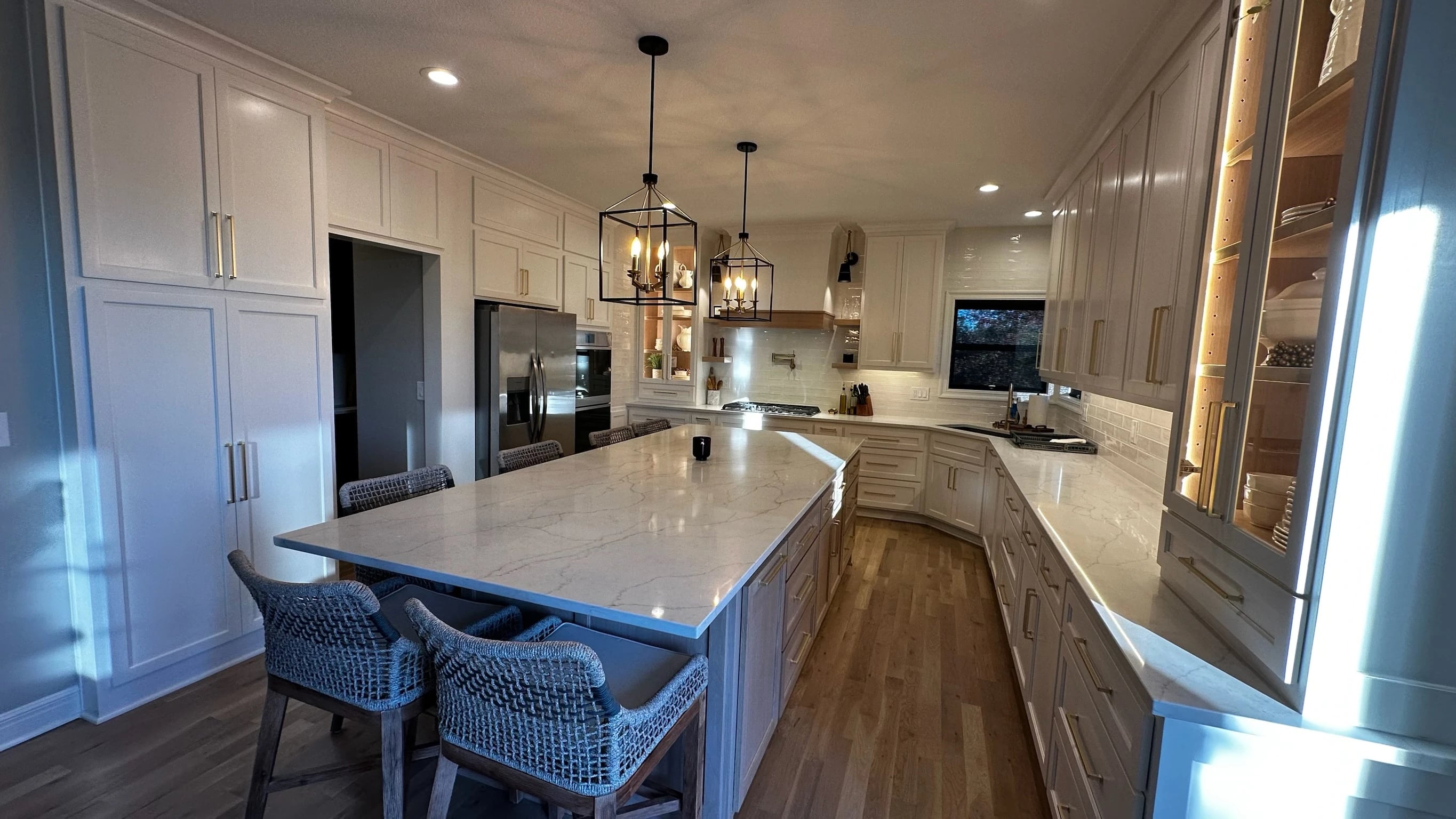 Wide kitchen island, white cabinetry and pendant lights
