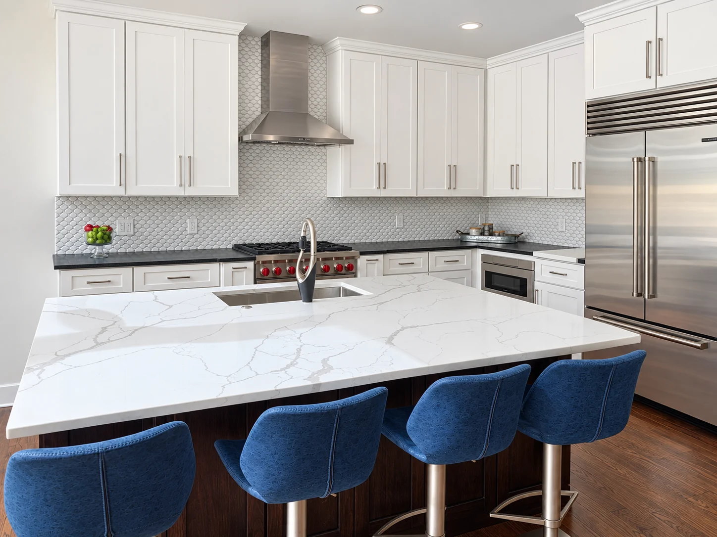 White shaker kitchen, veined island top, blue stools and stainless appliances