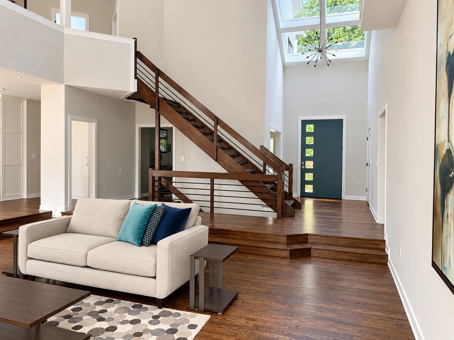 Wood staircase with black horizontal rails beside a bright living room