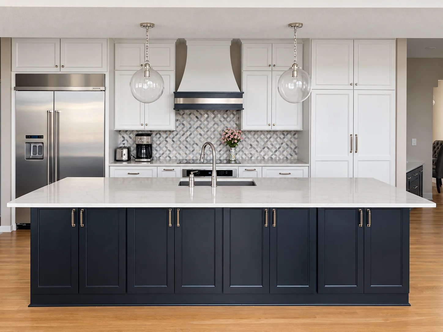 White kitchen cabinets, navy island, patterned backsplash and glass pendants