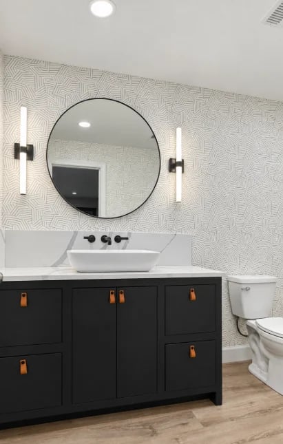 Dark half-bath vanity with a vessel sink, round mirror and patterned wall
