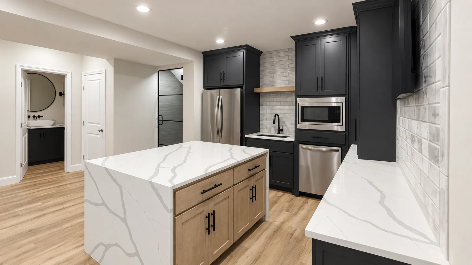 Veined waterfall island with wood cabinetry beside dark kitchen cabinets