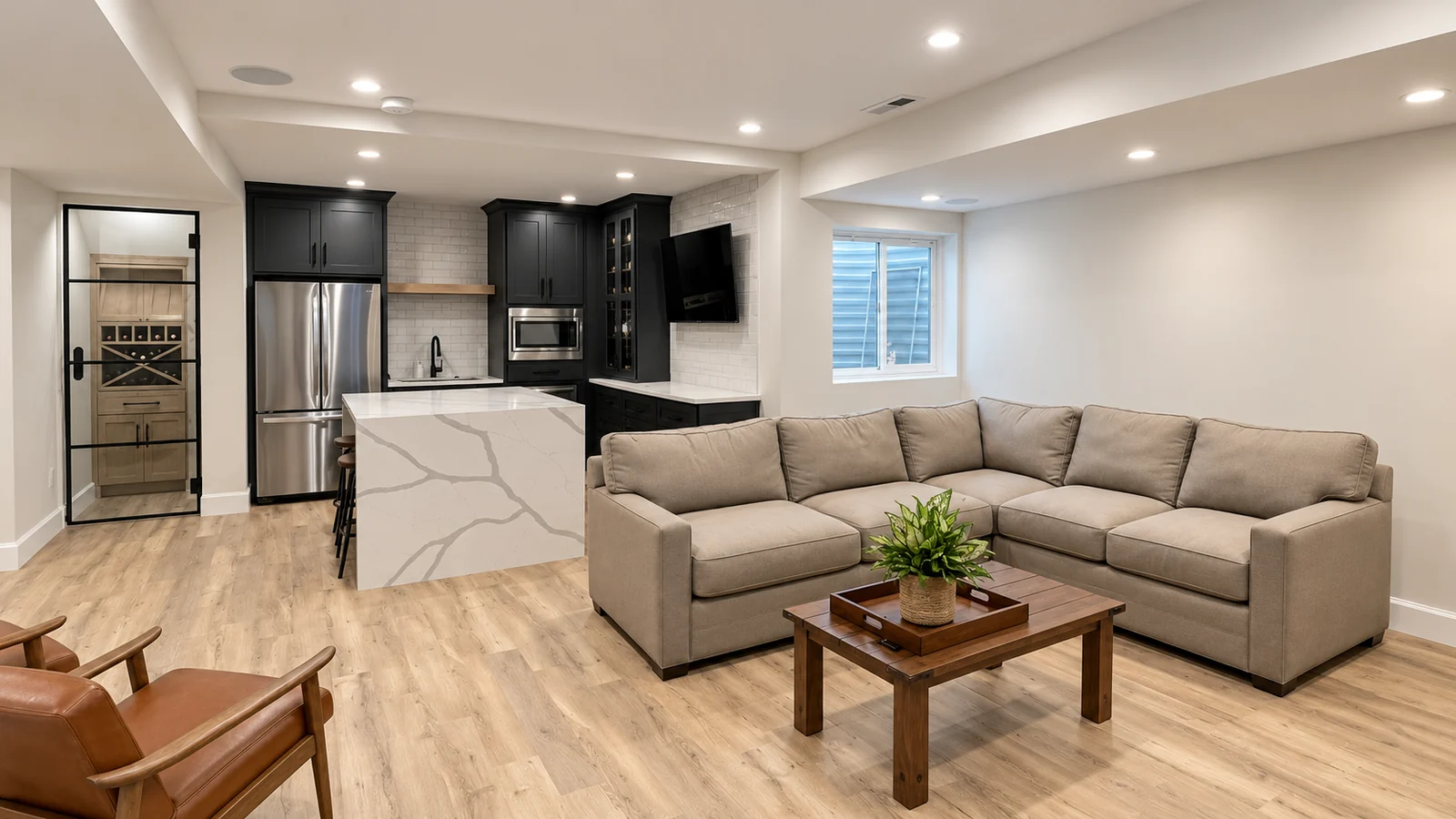 Sectional seating connected to a basement kitchen, island and glass-door wine nook