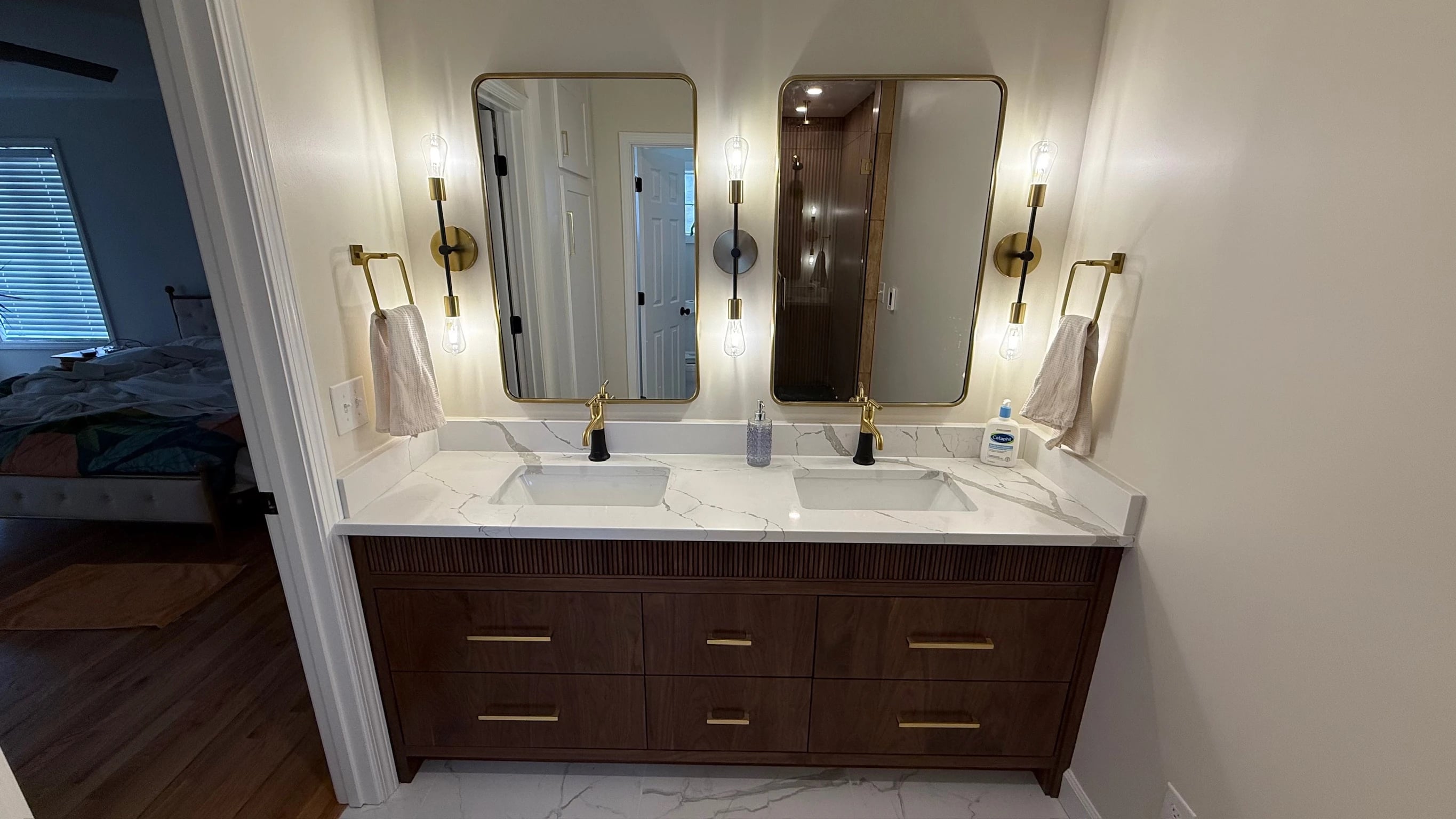 Fluted wood double vanity with paired mirrors and warm metal fixtures