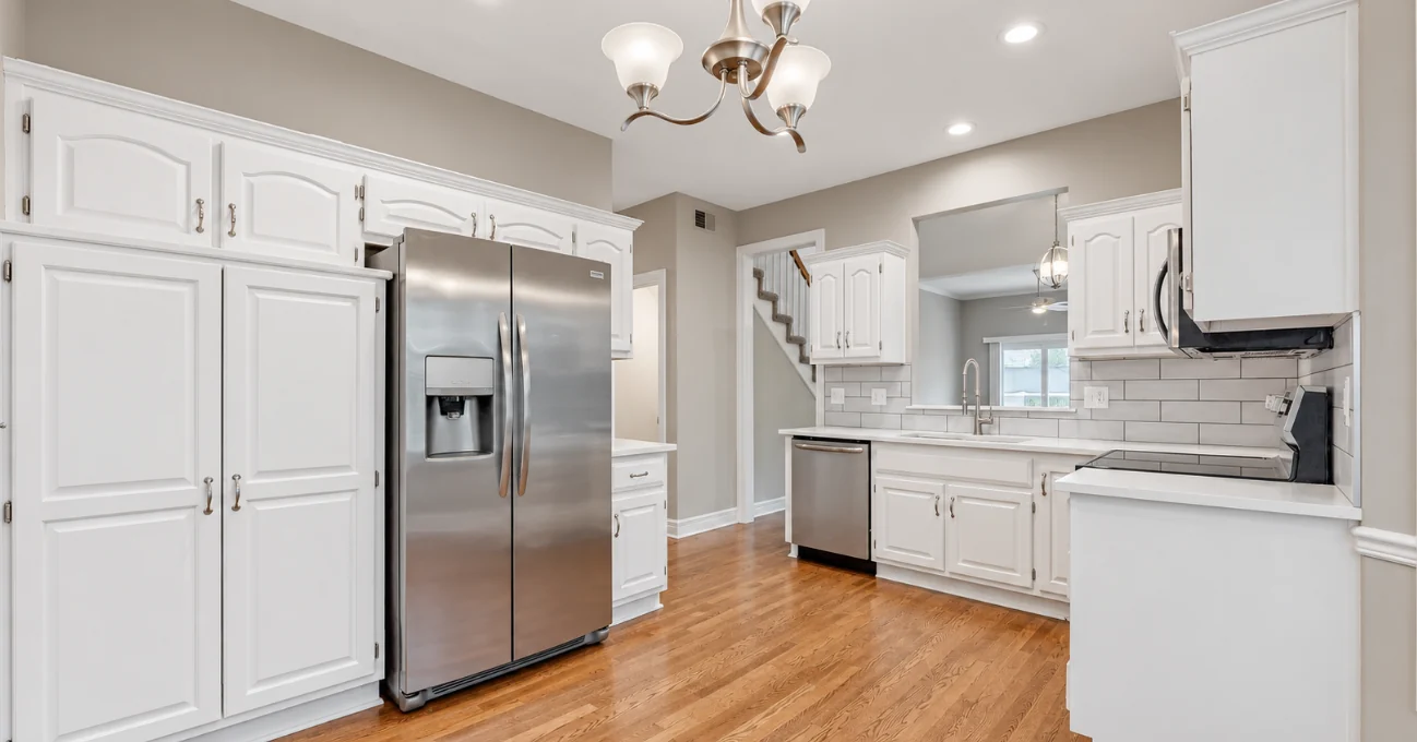 White kitchen cabinetry, stainless appliances and wood flooring
