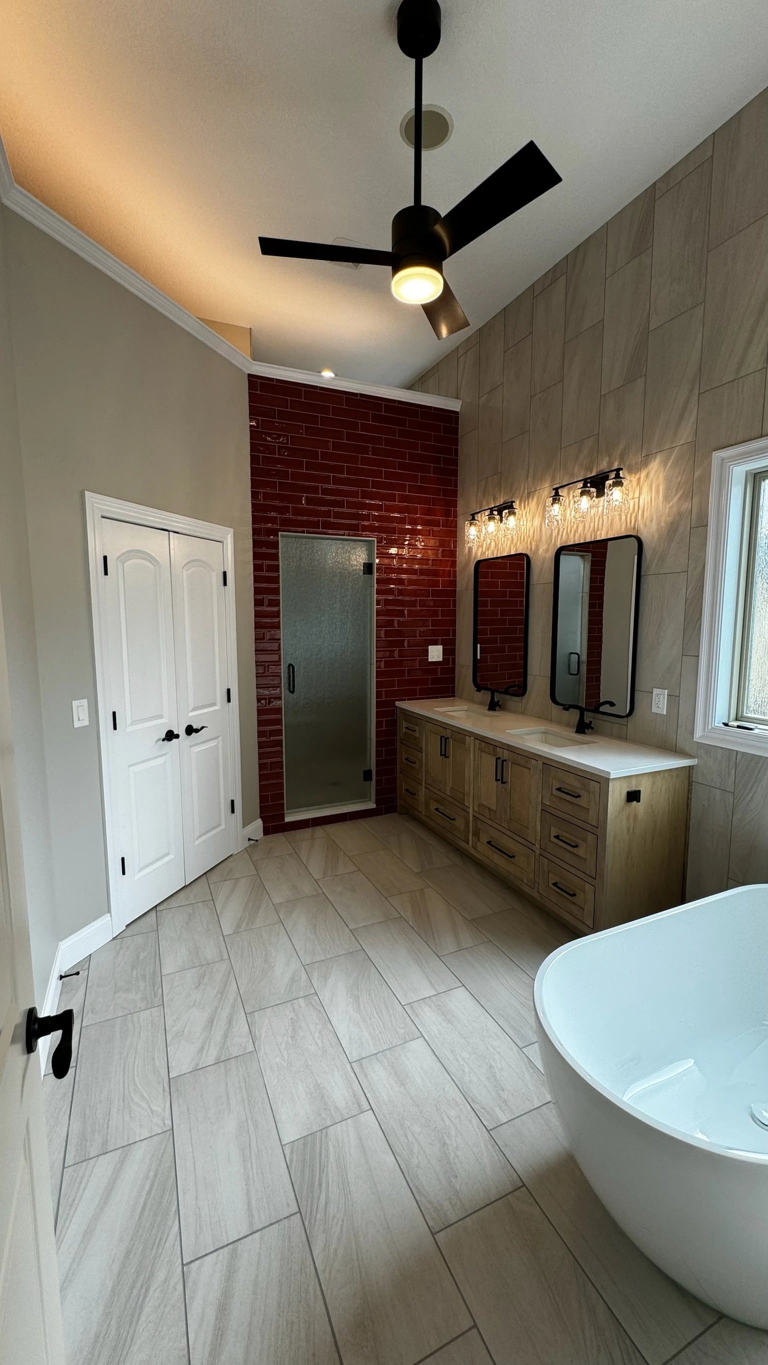 Tall tiled bathroom with custom wood vanity and shower beyond